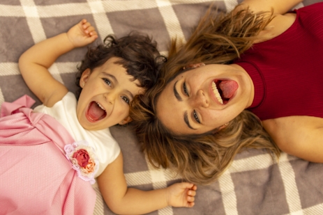 Madre e hija tumbadas sobre una manta en el suelo, sonrientes y felices.